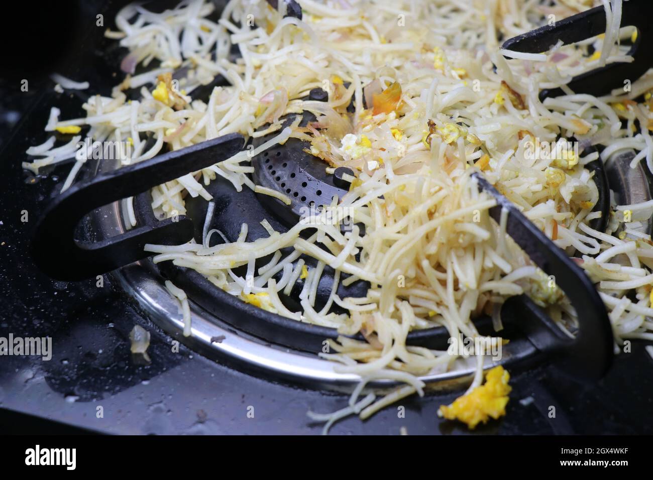 Noodles spilled on a stove top, food dropped on stove top while cooking with noodles all over gas burner Stock Photo