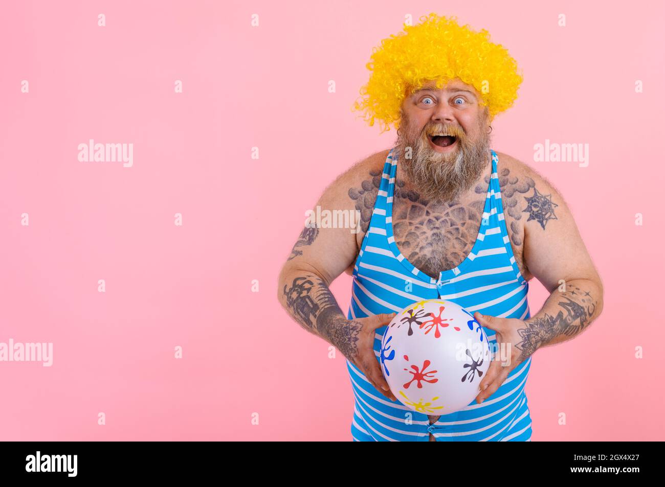 Fat amazed man with beard and wig play with the ball Stock Photo