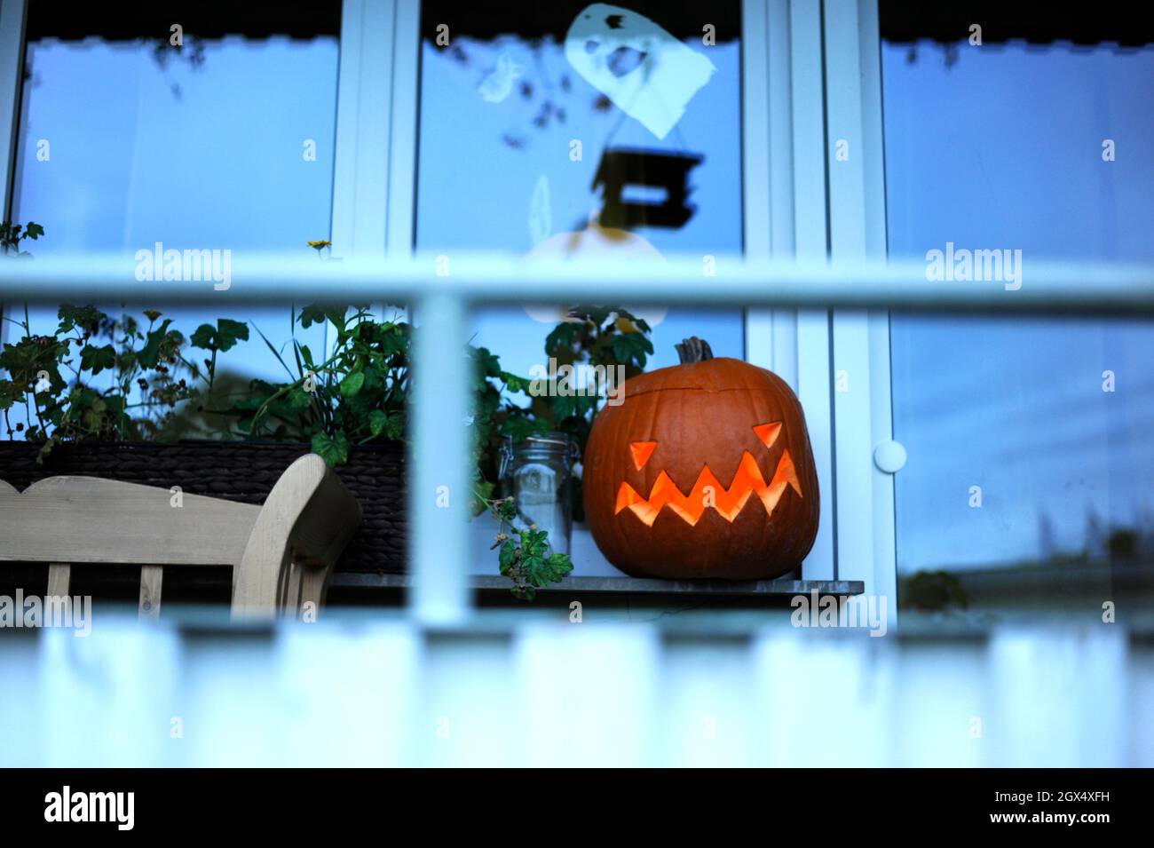 A Traditional Halloween Jack Lantern Pumpkin standing behind a Window. Stock Photo