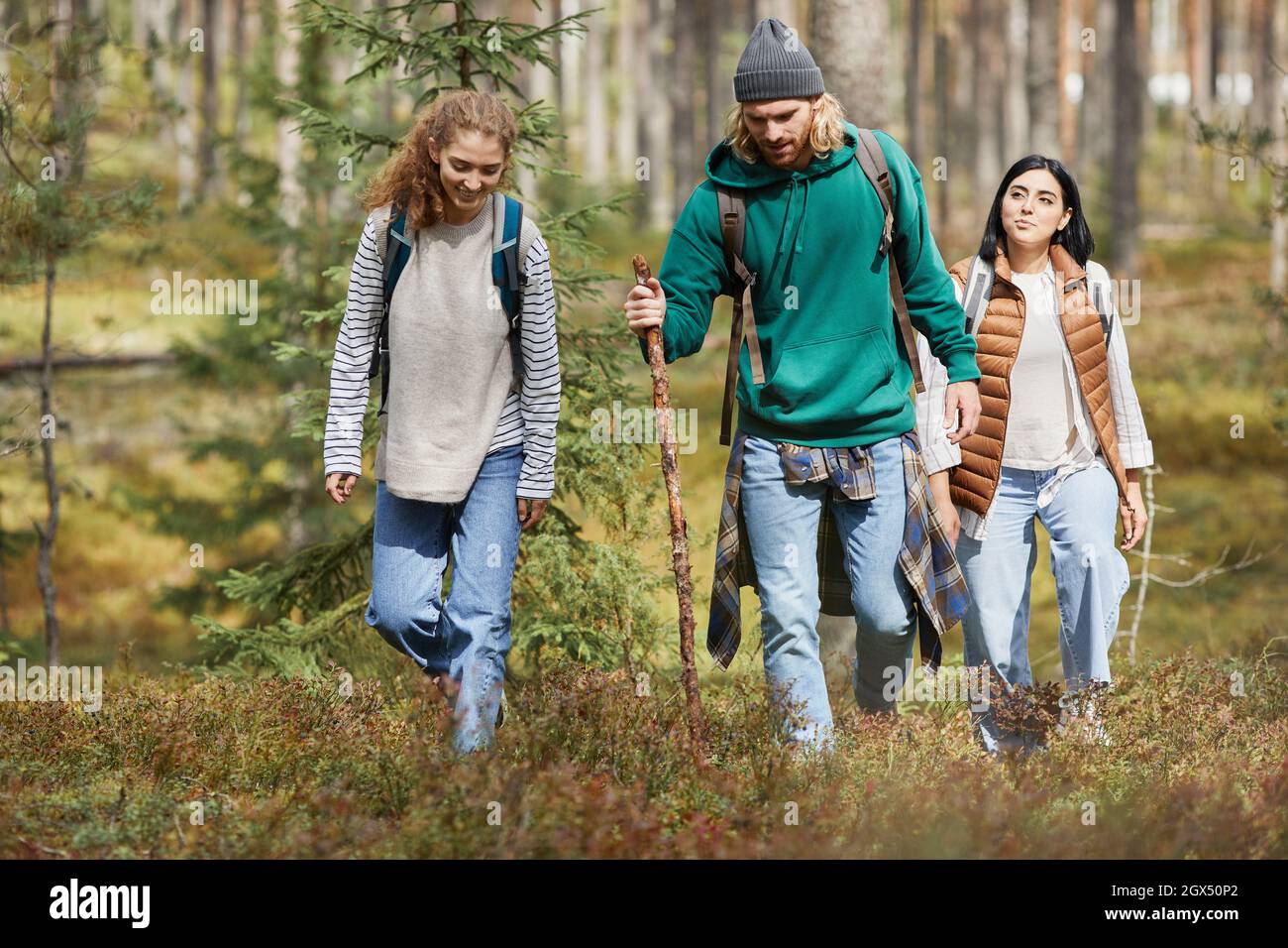 Young people walking in forest with backpacks while enjoying hiking ...
