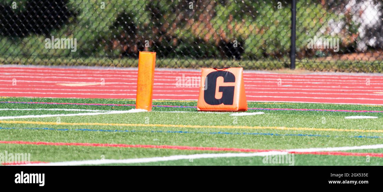 An orange pylon marks the end zone with a marker with the letter G on a football field Stock