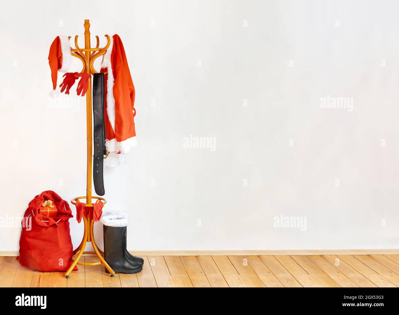The equipment of Santa Claus hangs on the coat hook in a empty room with wooden floor. Stock Photo