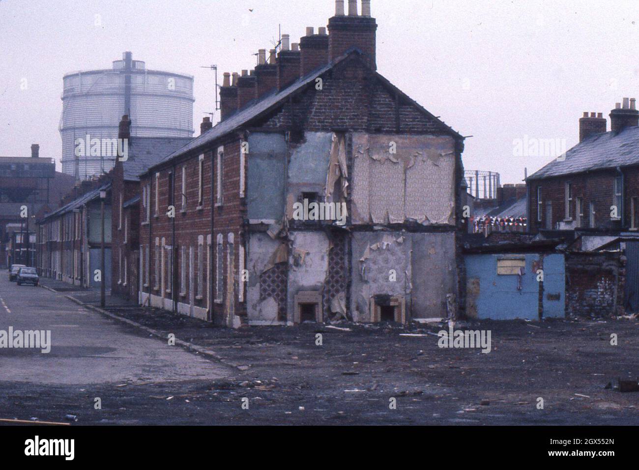 Terrace houses in Salisbury Street, Belfast, half-demolished, against a backdrop of Belfast gas works in 1982. Stock Photo