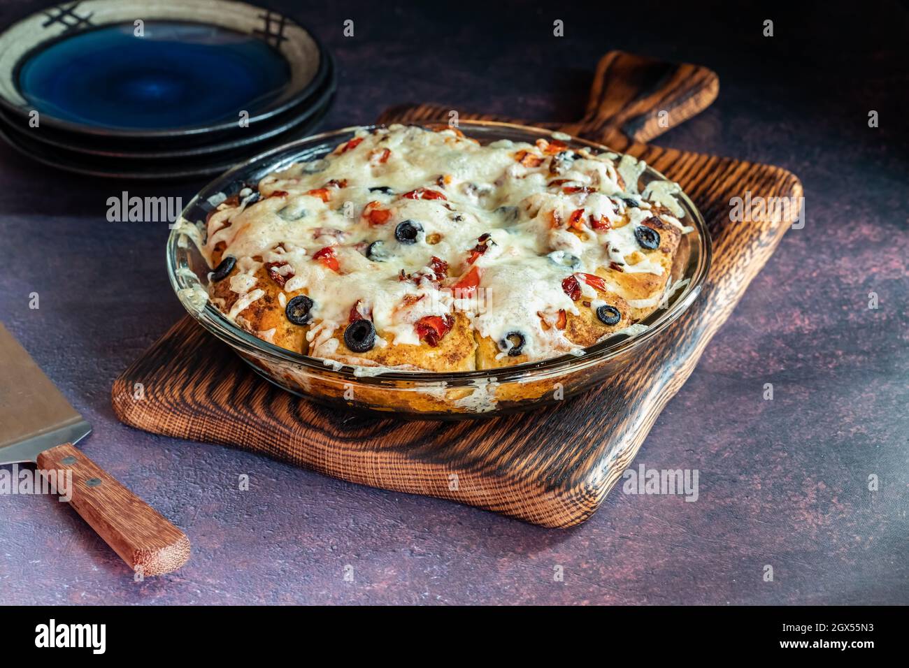 Freshly baked homemade pizza pull apart bread cooling on a wooden board. Stock Photo
