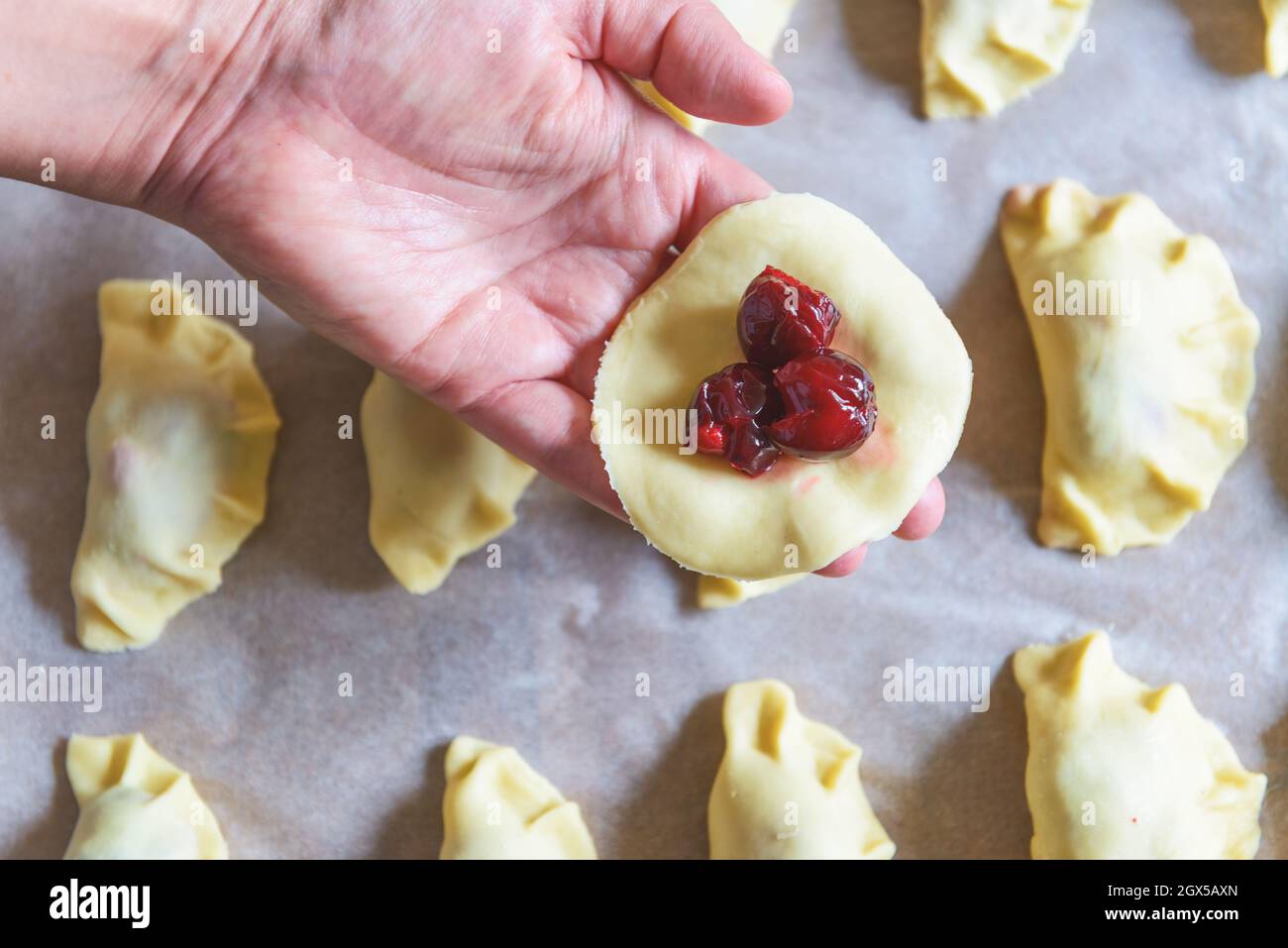 Making dumplings filled with sour cherry with sugar Stock Photo