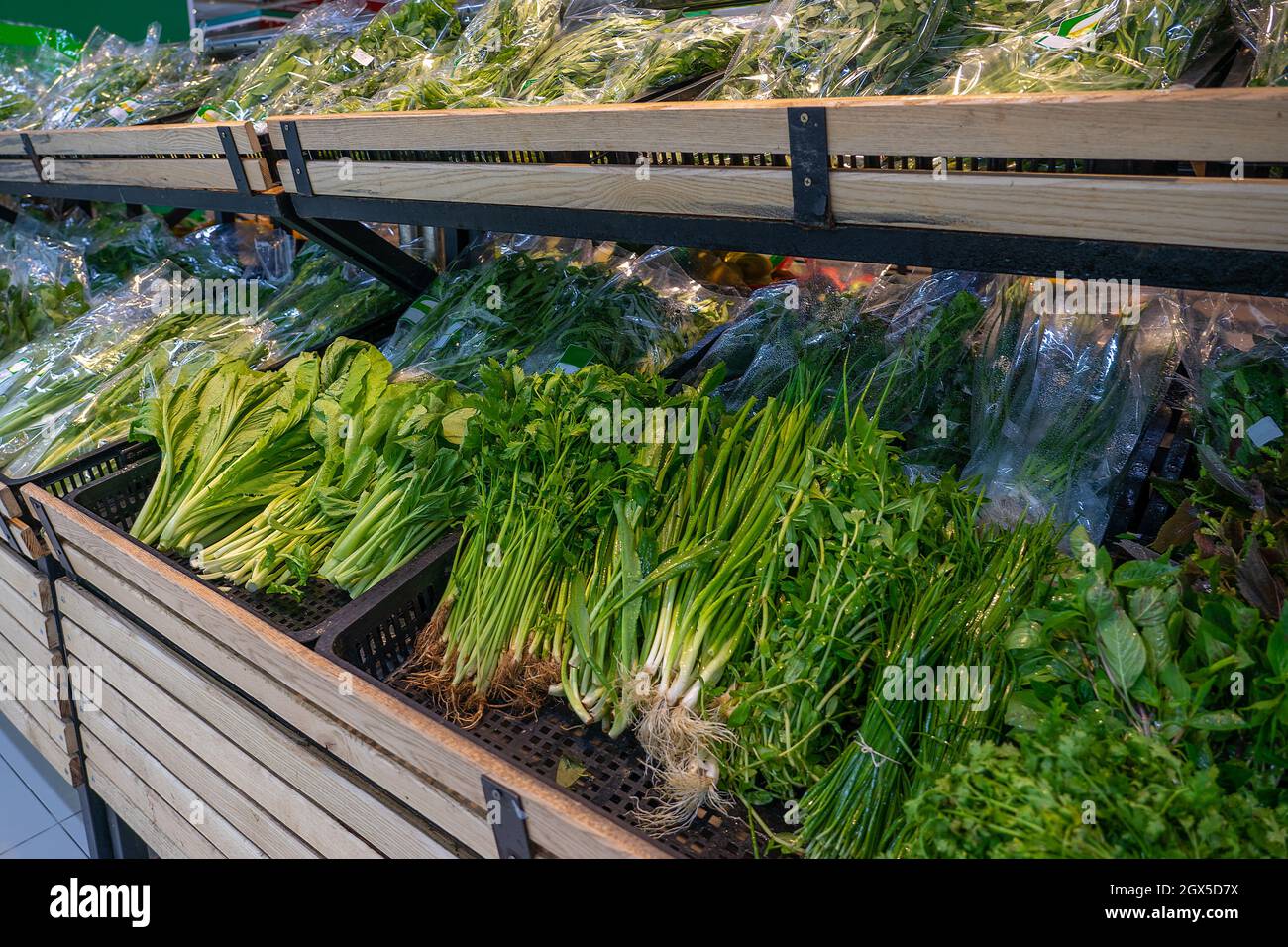 Various fresh herbs on the wooden counter of the grocery shop. Vegetable department in the supermarket. Stock Photo
