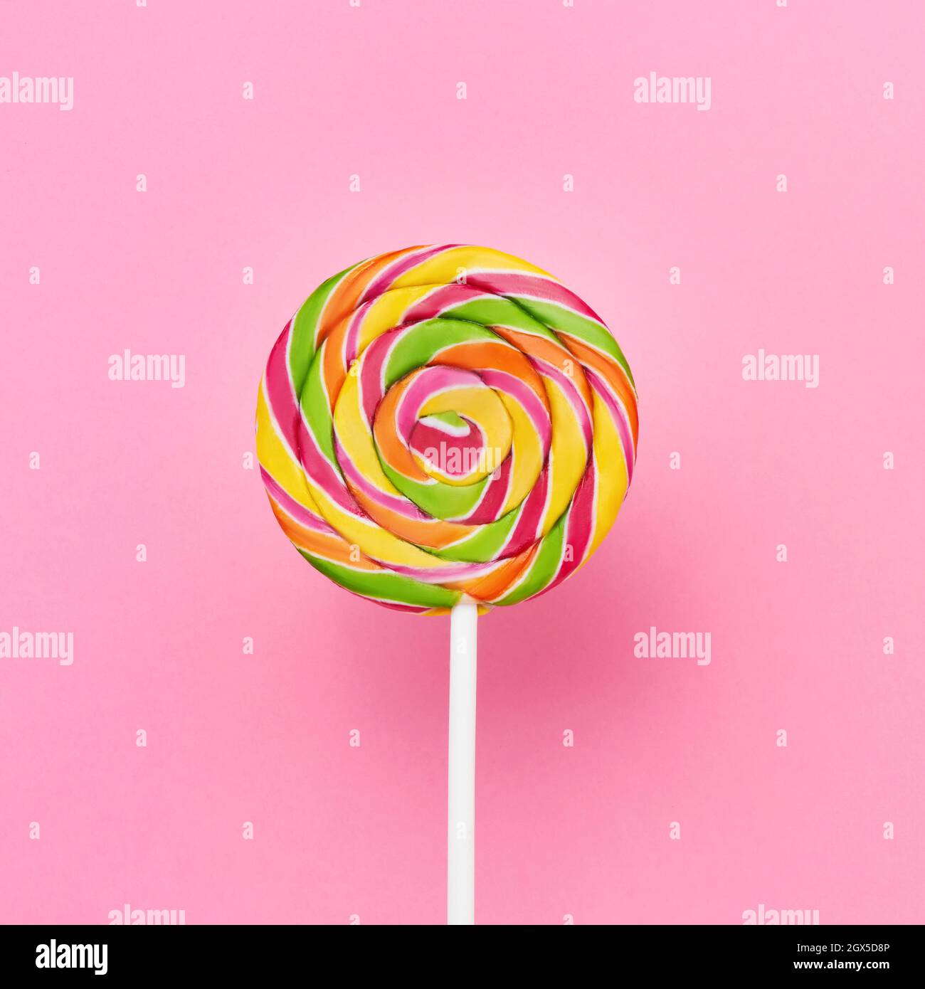 https://c8.alamy.com/comp/2GX5D8P/rainbow-lollipop-swirl-on-a-white-stick-over-pink-background-top-view-copy-space-for-text-2GX5D8P.jpg