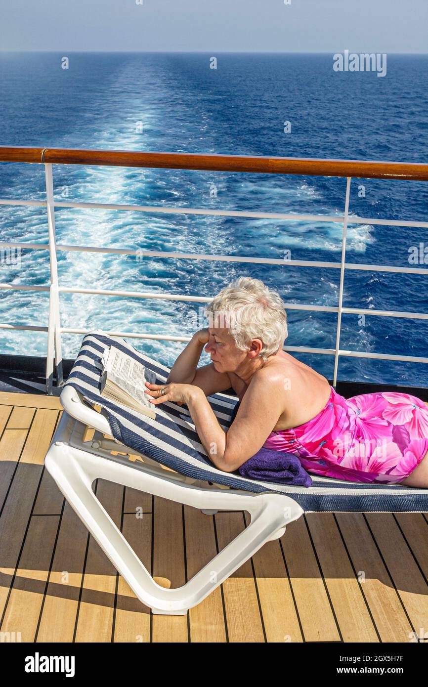 New York City Atlantic Ocean Holland America Line Caribbean cruise,ms Noordam Lido Deck,senior citizen woman female sunbathing lounge chair reading Stock Photo