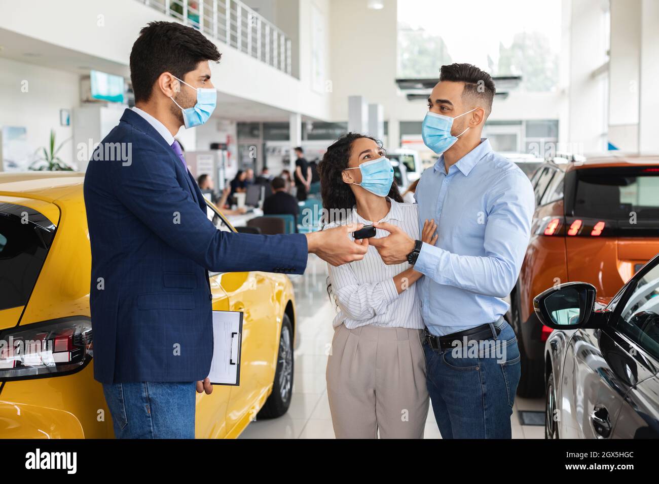 Sales manager giving middleeastern family key from auto Stock Photo