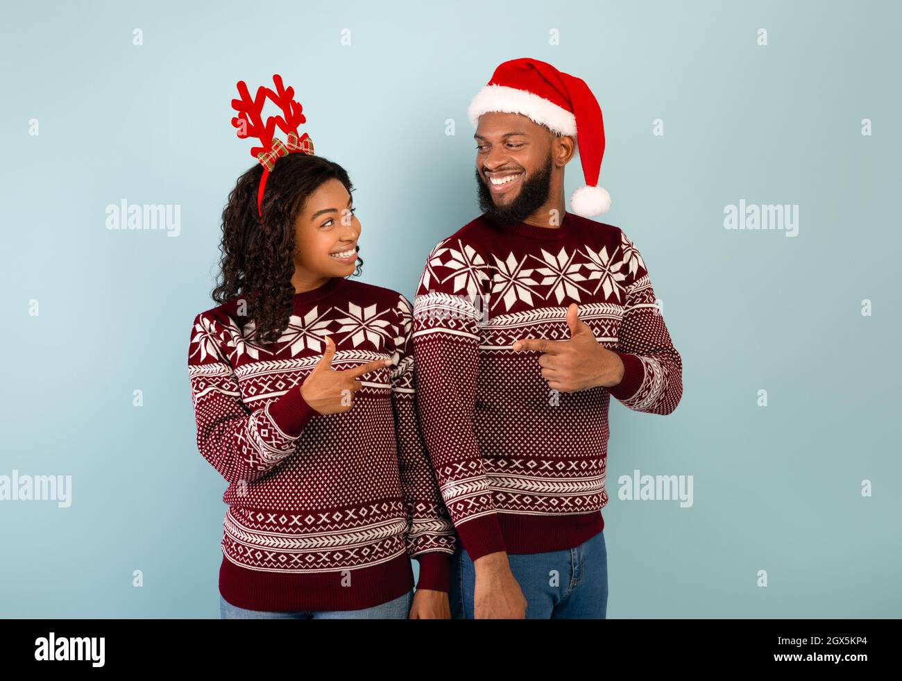 New Year 2022 Celebration. Young Black Couple In Christmas Sweaters Pointing Index Fingers At Each Other Stock Photo - Alamy