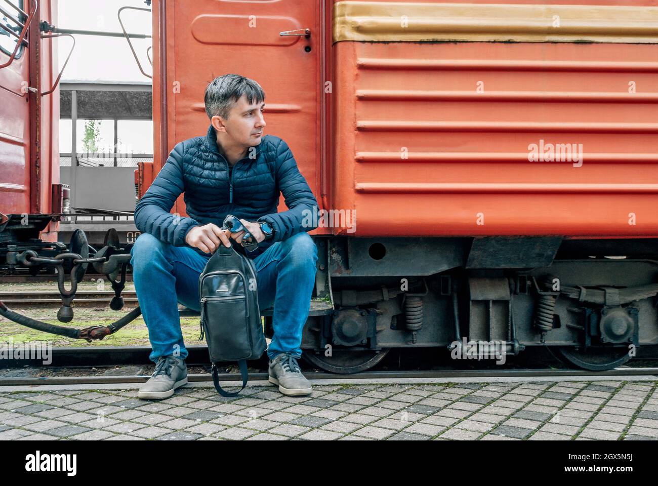 Man sits on the bandwagon of an old train, looks to the right Stock Photo