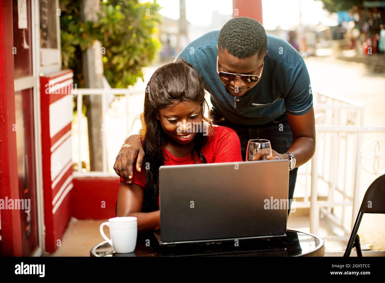 happy beautiful young african couple in a restaurant using a laptop ...