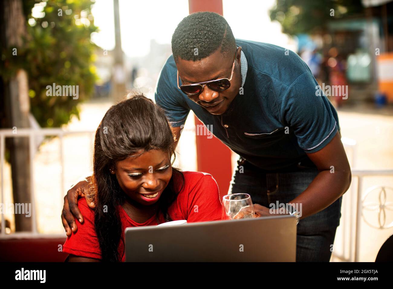 happy beautiful young african couple in a restaurant using a laptop ...