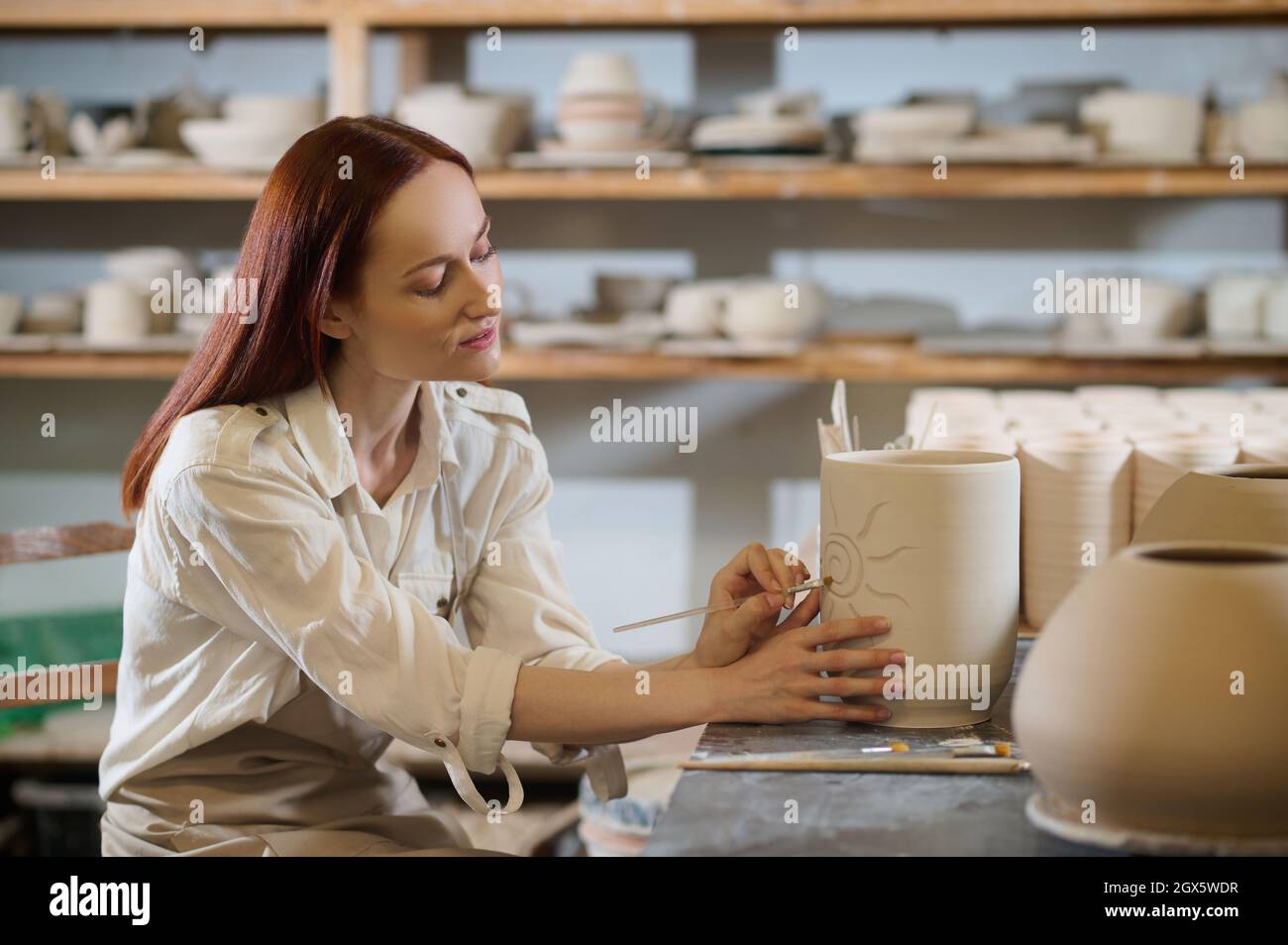 A pretty woman looking involved while painting the pot Stock Photo - Alamy