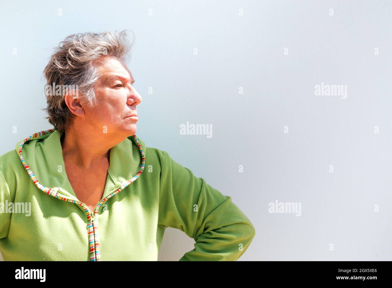 Profile portrait of an elderly woman with short gray hair looking angry on a white background. Photo with copyspace Stock Photo
