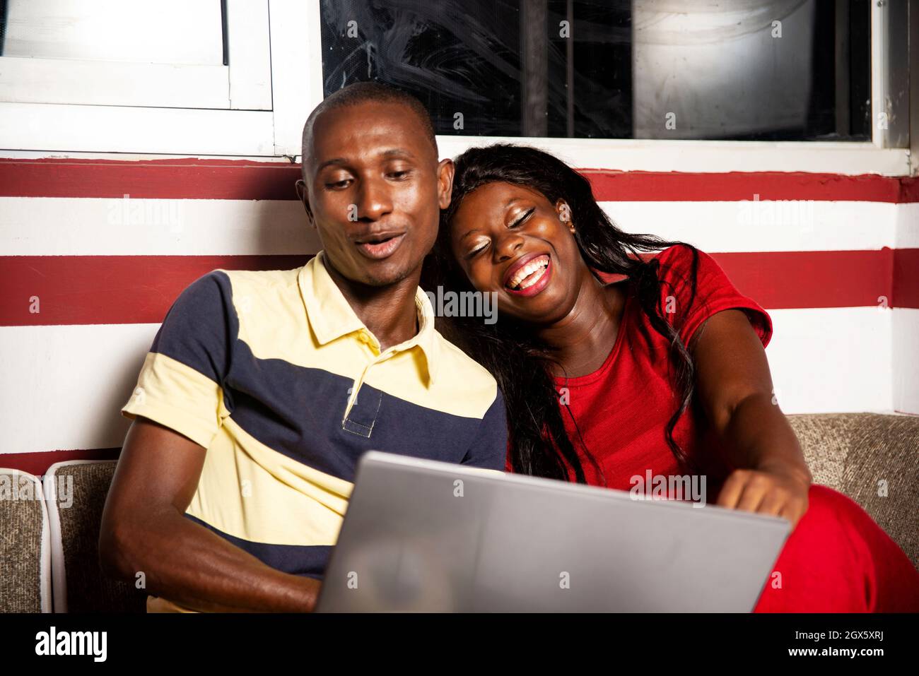beautiful young african couple sitting indoors and working using a ...