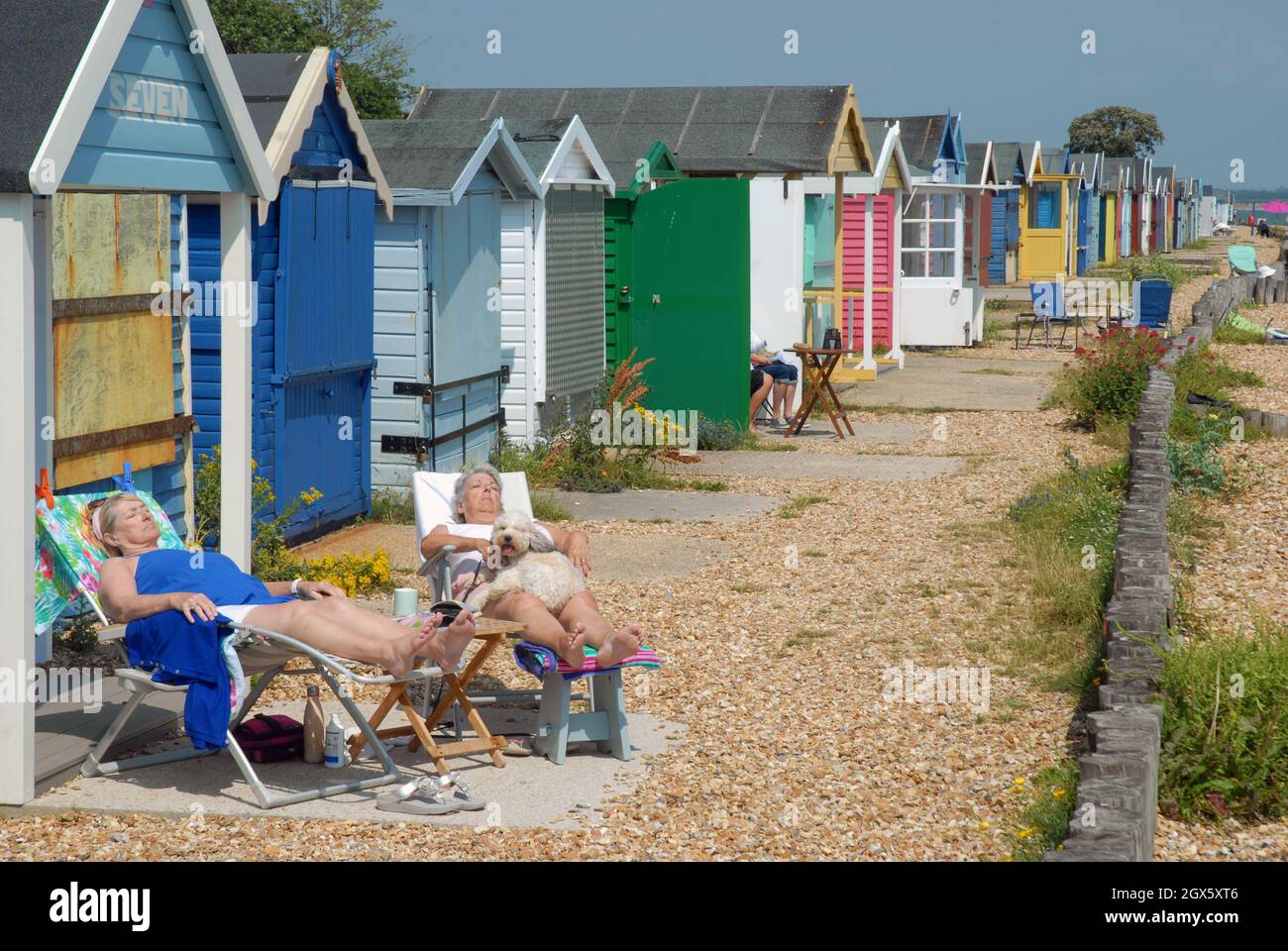 Two woman asleep on chairs outside their beach hut, Calshot Beach, Calshot, Hampshire, UK. Stock Photo