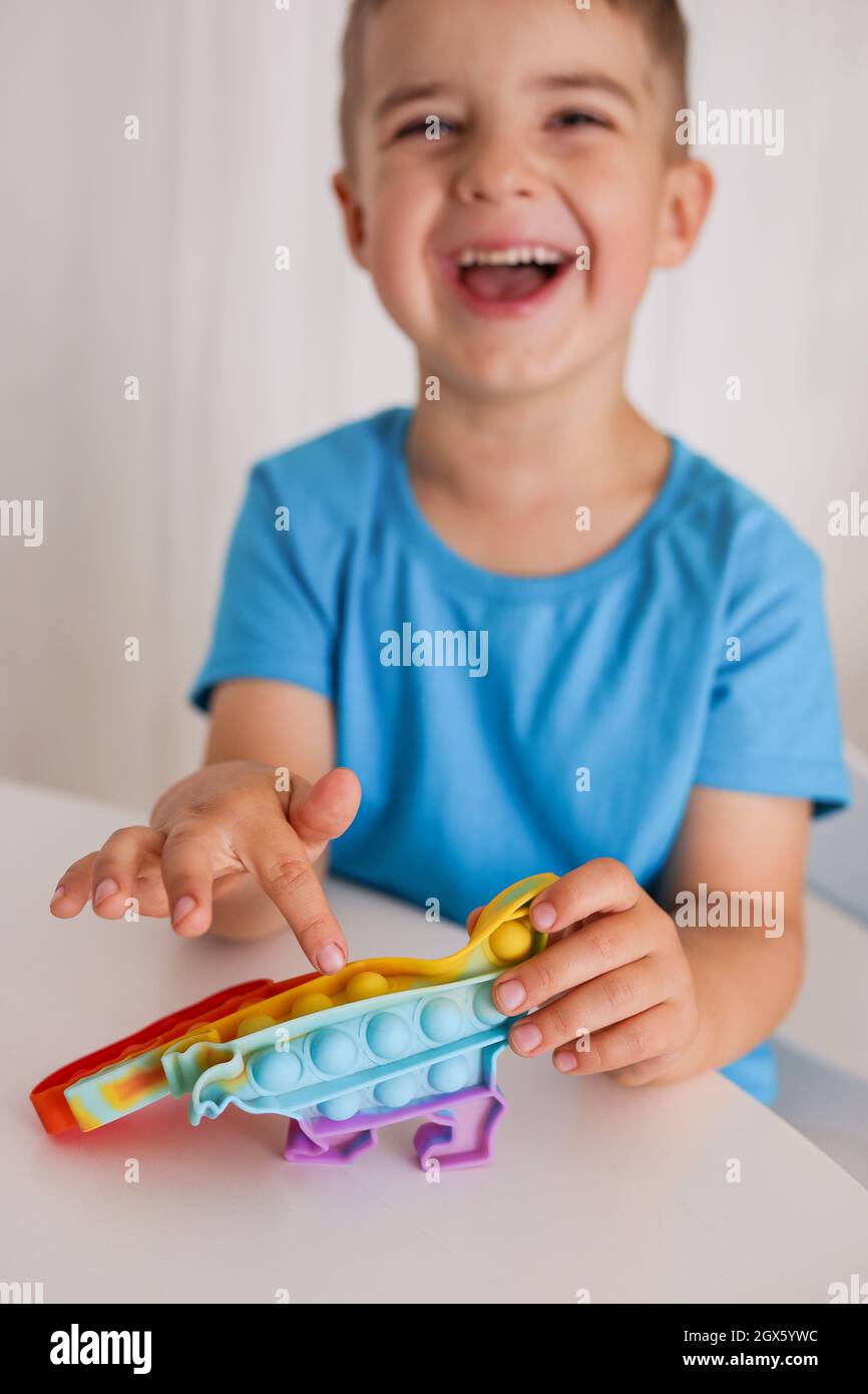 Little boy plays with rainbow Pop it fidget toy. Antistress children game.  Children's trendy silicone toys pop it to relieve stress and develop hand  Stock Photo - Alamy