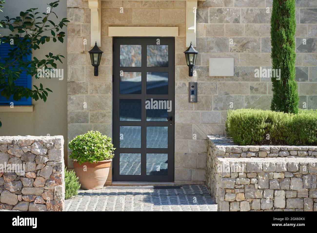 Modern house facade with stone finished wall, glass door and bushes in europe Stock Photo