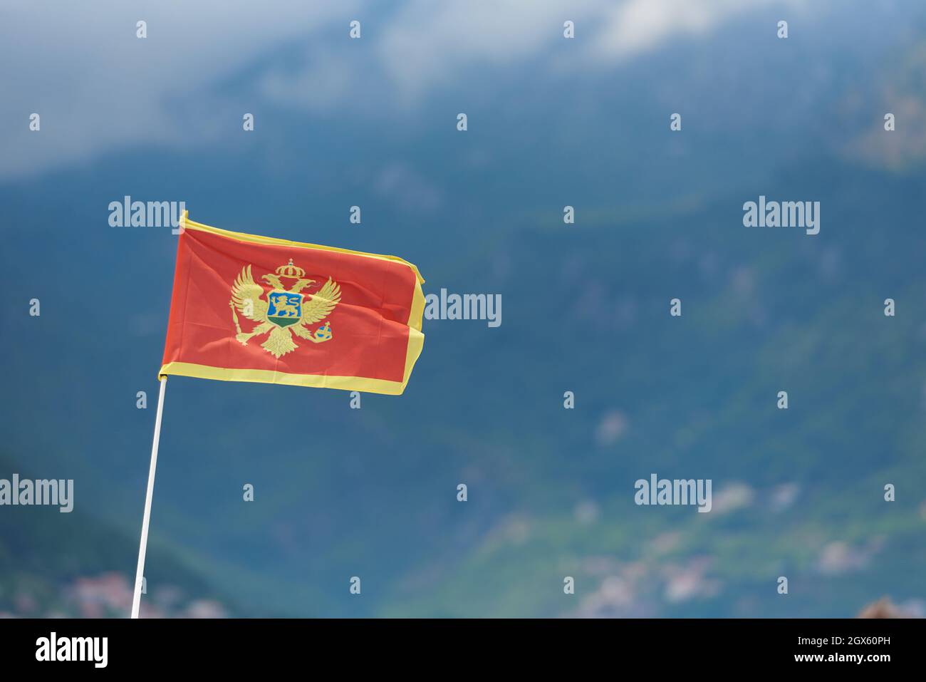 Bright and red flag of Montenegro on a background of mountains with text space Stock Photo
