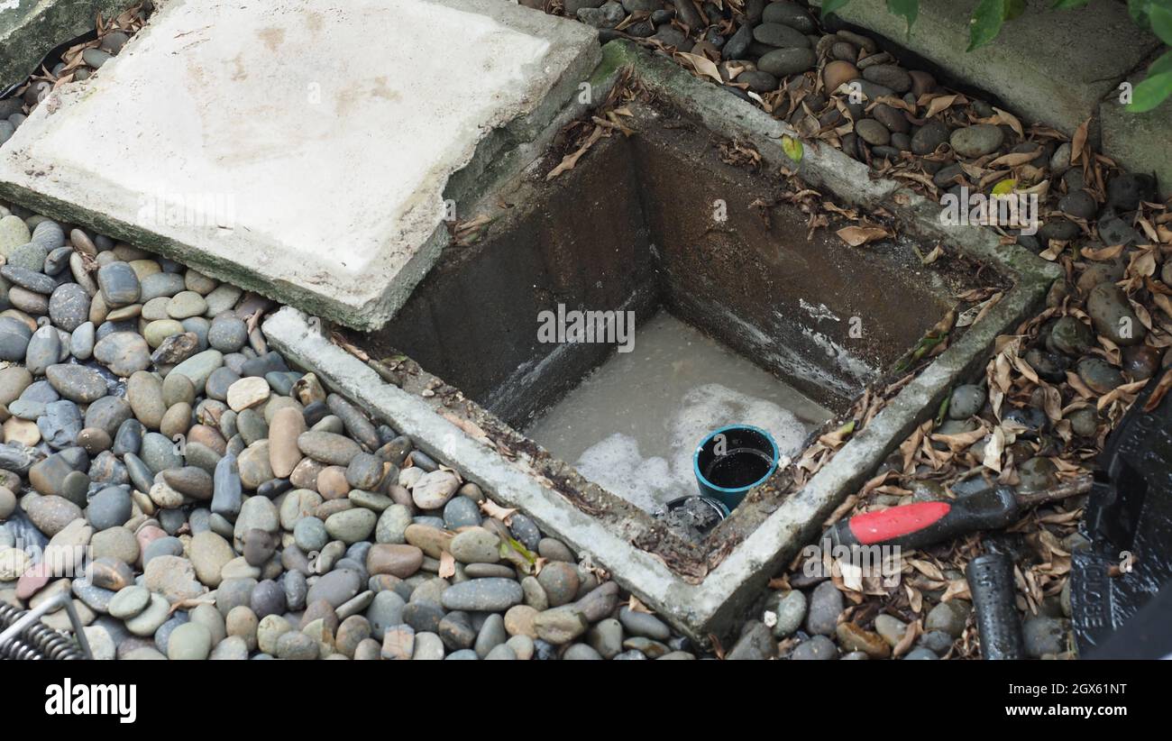 Drain cleaning. Plumber repairing clogged grease trap with auger