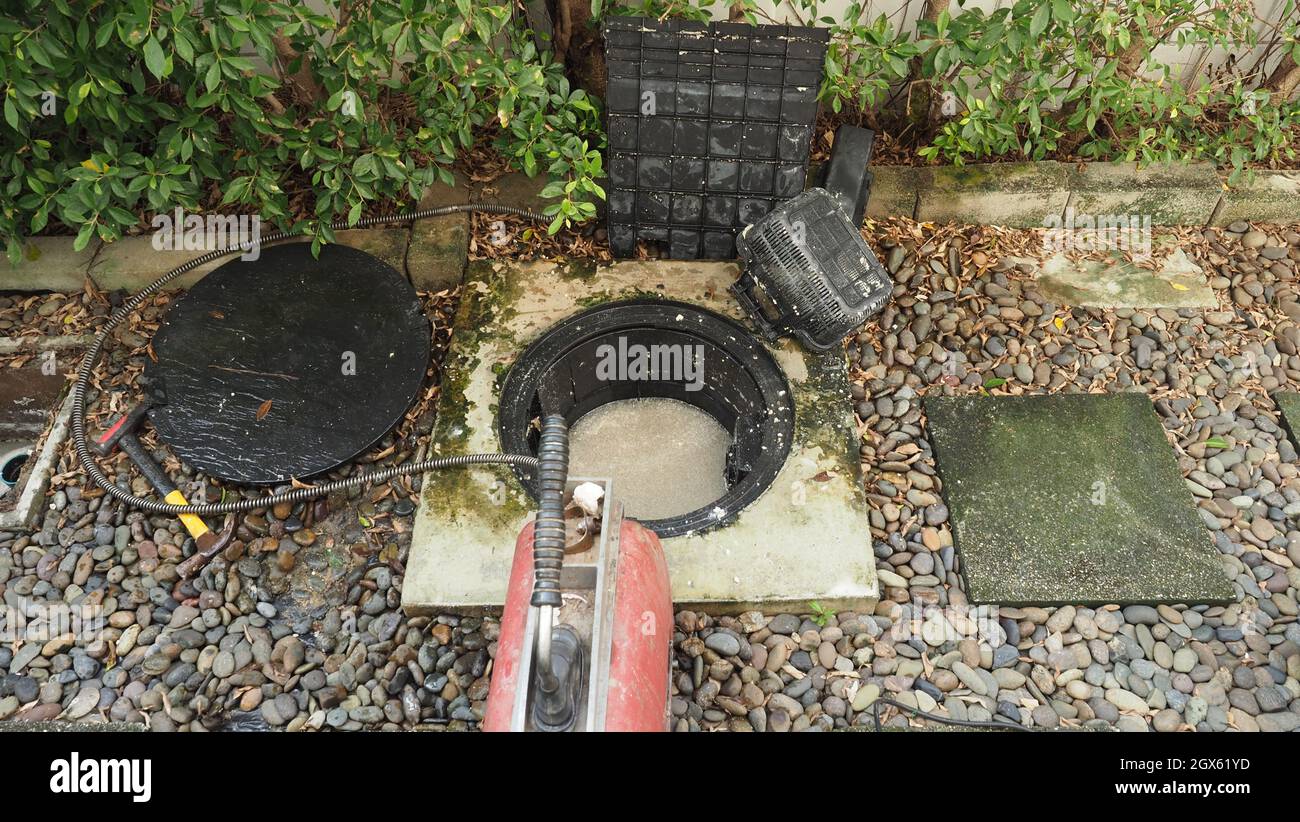 Drain cleaning. Plumber repairing clogged grease trap with auger