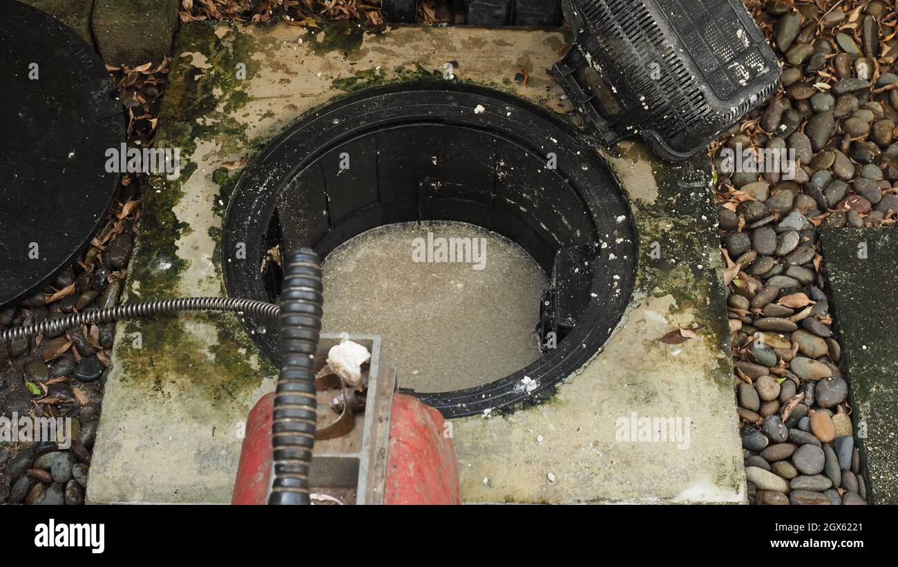 Drain cleaning. Plumber repairing clogged grease trap with auger