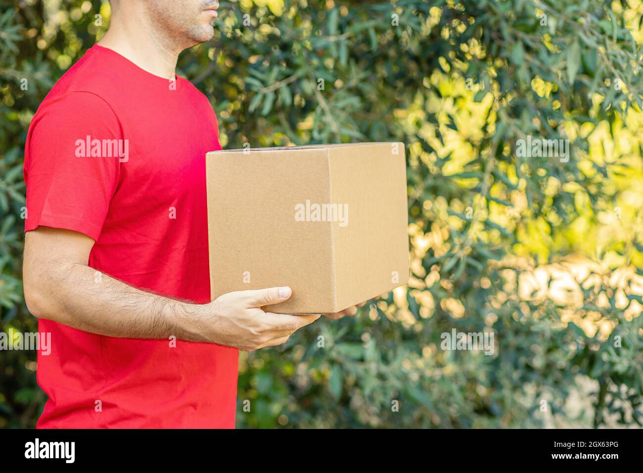 Delivery man holding cardboard boxes on the farm. Express delivery Courier order online shopping concept Organic food  Stock Photo