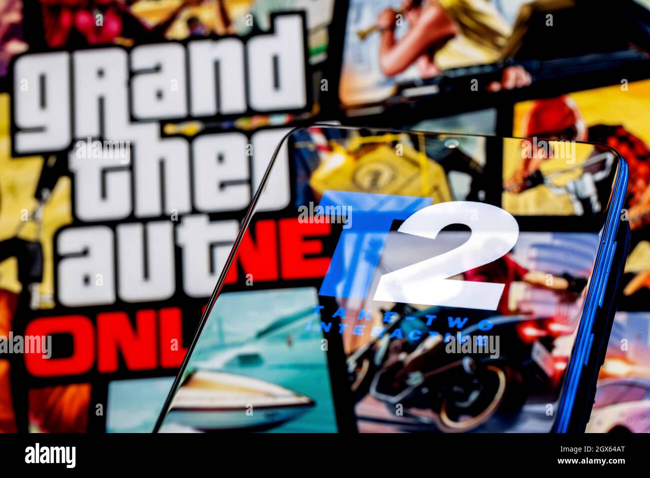Take-Two logo on smartphone screen. A frame from the GTA game on the background. Stock Photo