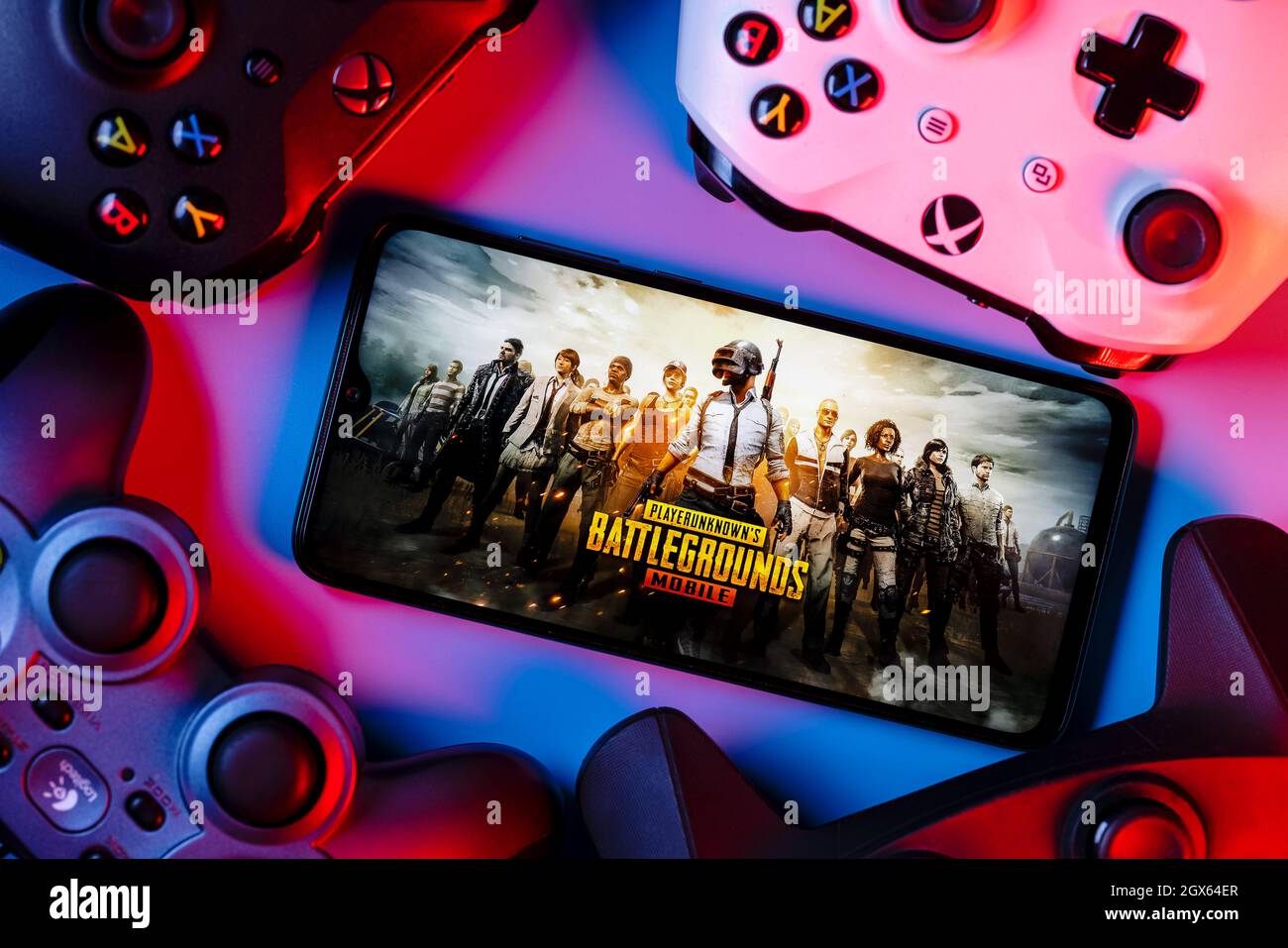 A smartphone with the frame from PUBG Mobile on the screen surrounded by gamepads. Stock Photo