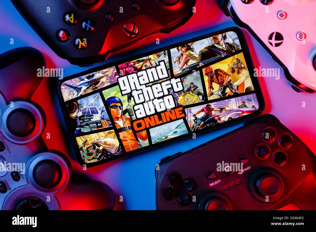 A smartphone with the frame from GTA Online on the screen surrounded by gamepads. Stock Photo