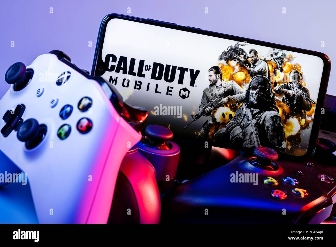 A smartphone with the frame from Call of Duty on the pile of the gamepads. Stock Photo
