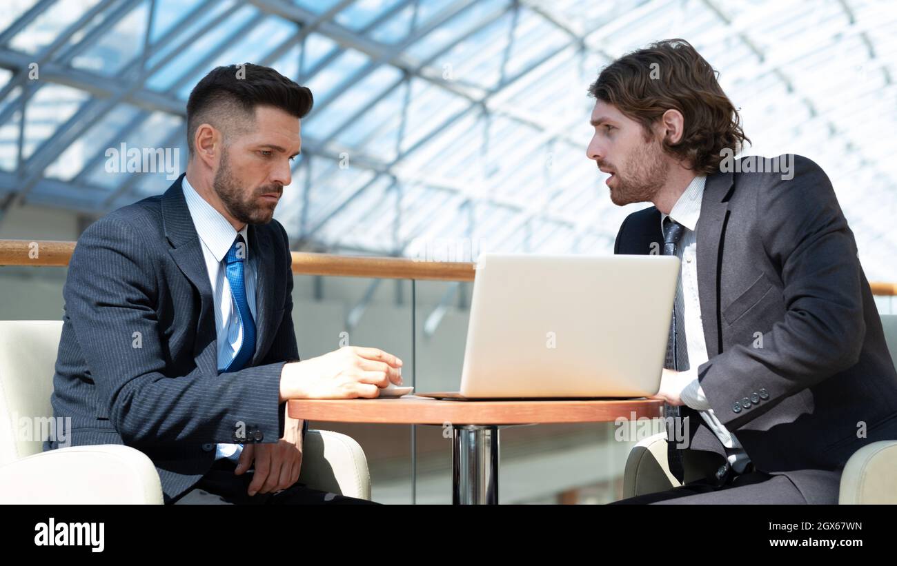 Two business men in modern office building cafe working with laptop Stock Photo
