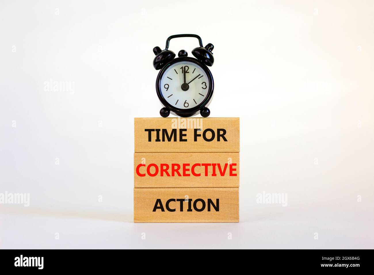 Time for corrective action symbol. Wooden blocks with words 'Time for corrective action' on a beautiful white background. Black alarm clock. Business, Stock Photo