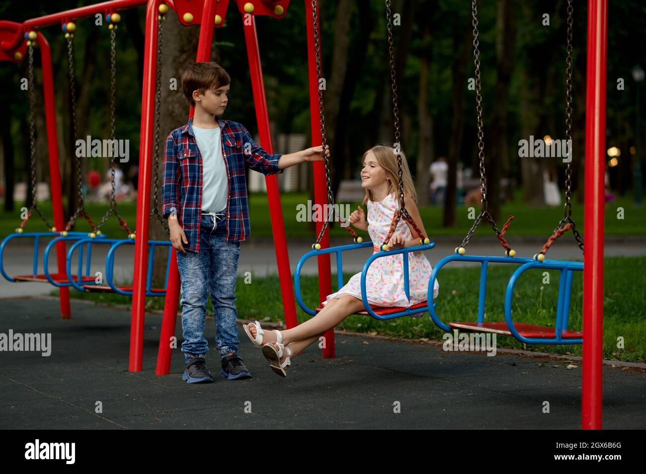 Children's romantic date, boy and girl on swings Stock Photo