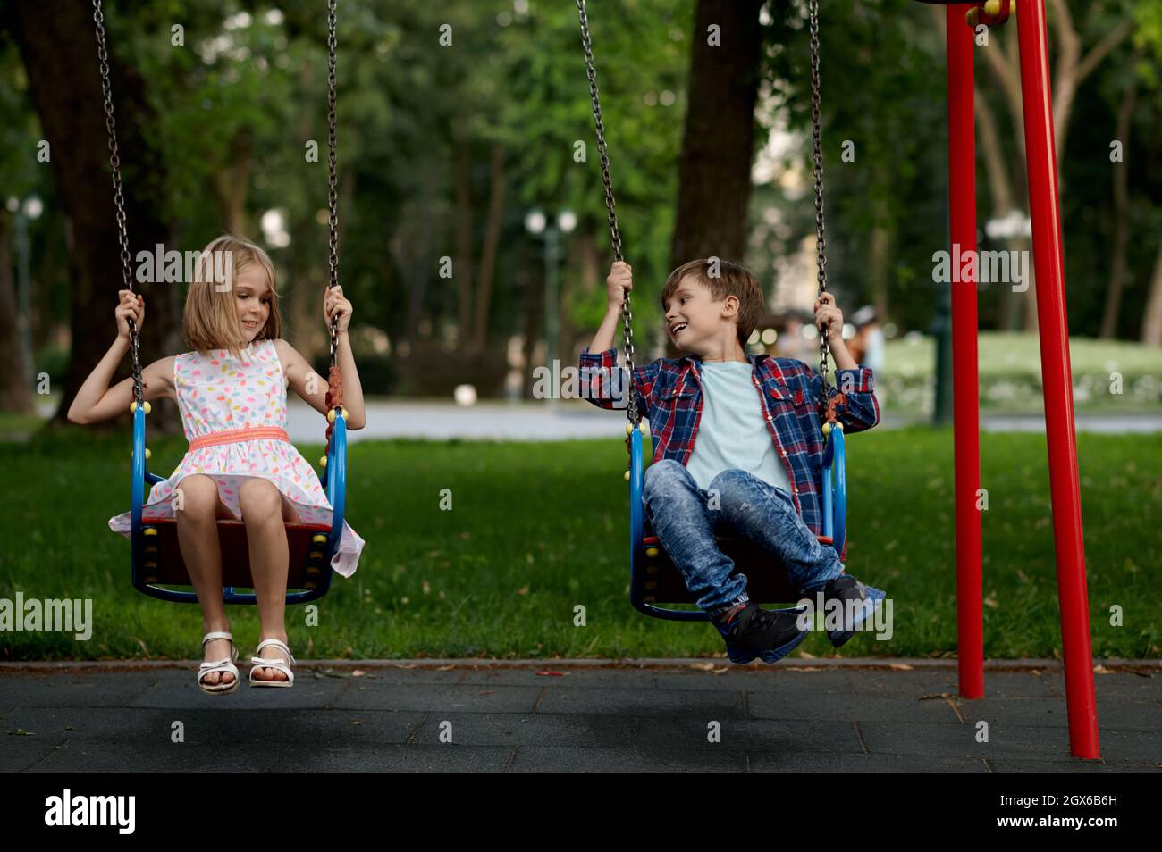 Boy and girl sharing swing on summer day in Sweden Stock Photo - Alamy