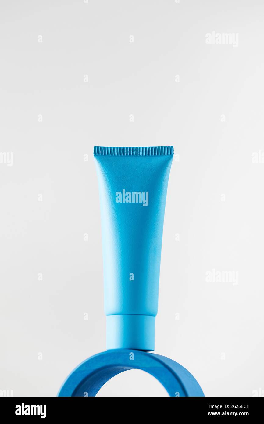 Blue tube with cosmetic product, cream on a pedestal on a light