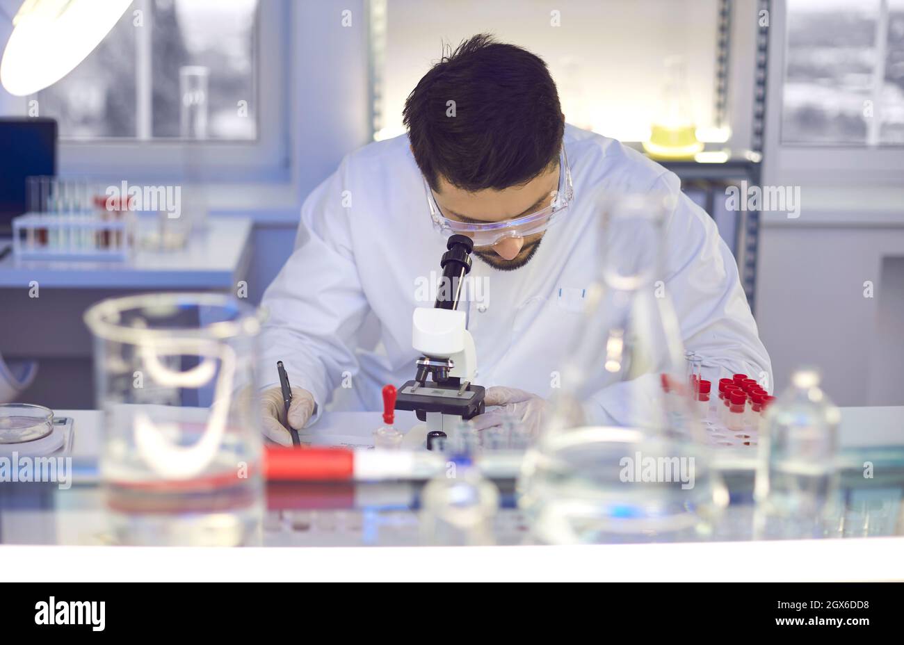 Young man in the laboratory looks through a microscope. Stock Photo