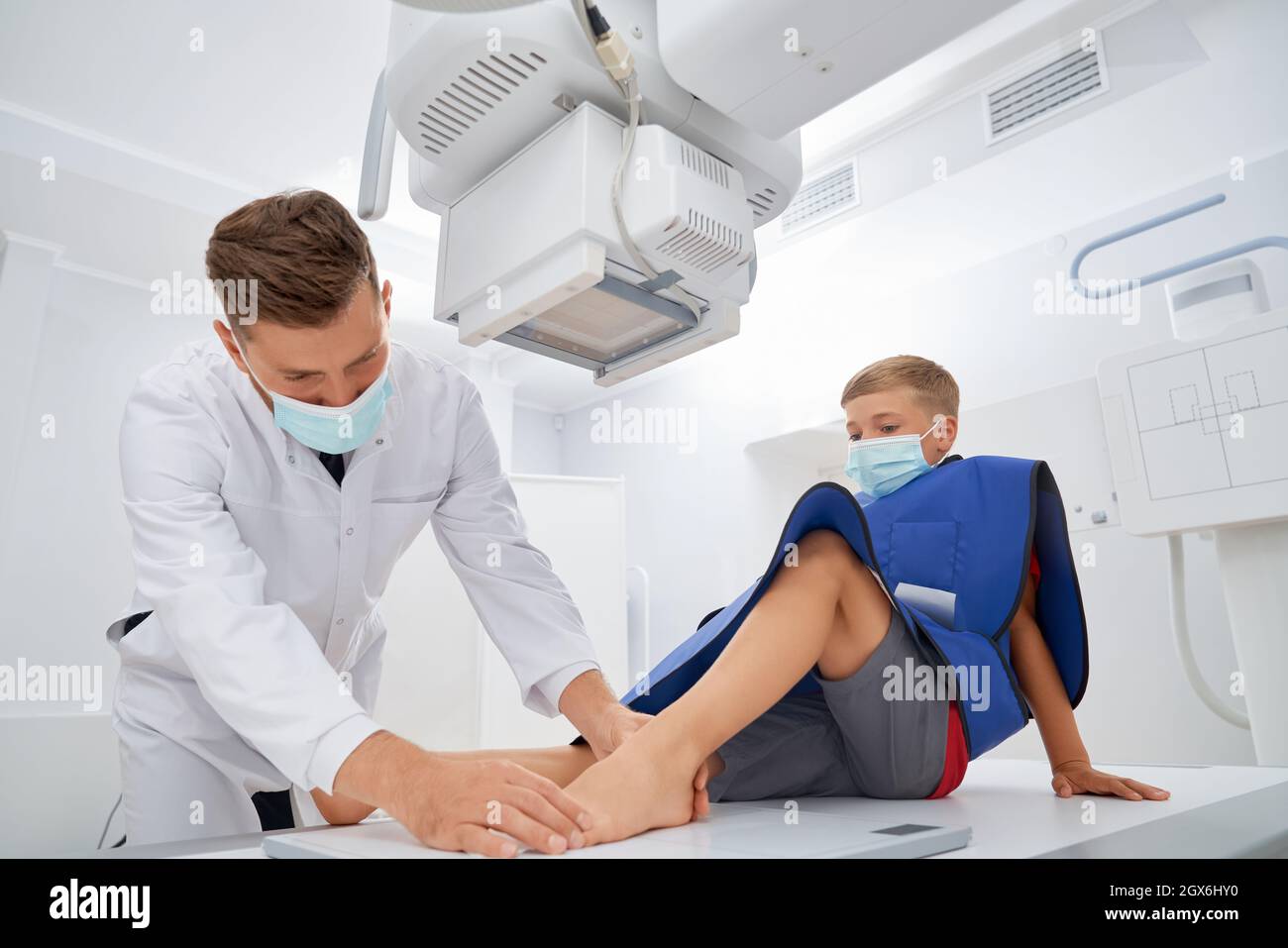 Professional doctor in white uniform doing medical examination before ultrasound diagnostic. Boy sitting in clinic and check in leg after pain. Concept of kids medicine. Stock Photo