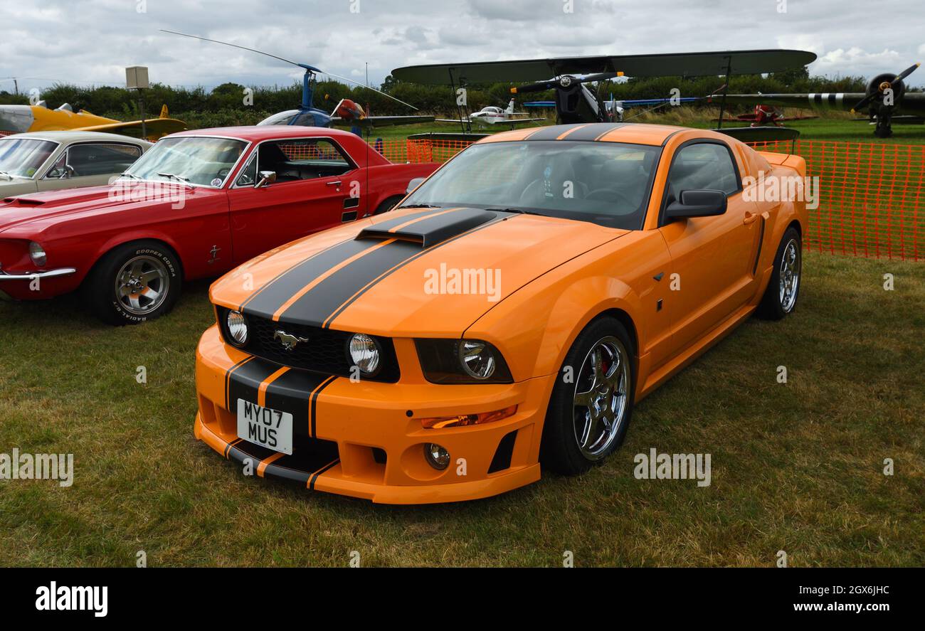Classic  Orange Ford Mustang S197  at  airstrip. Stock Photo