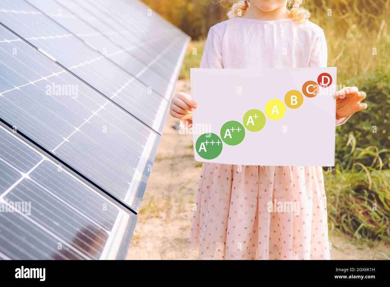 Energy consumption labeling scheme. Solar power and energy efficiency concept. Girl child standing next to home solar farm with help reduce electricit Stock Photo