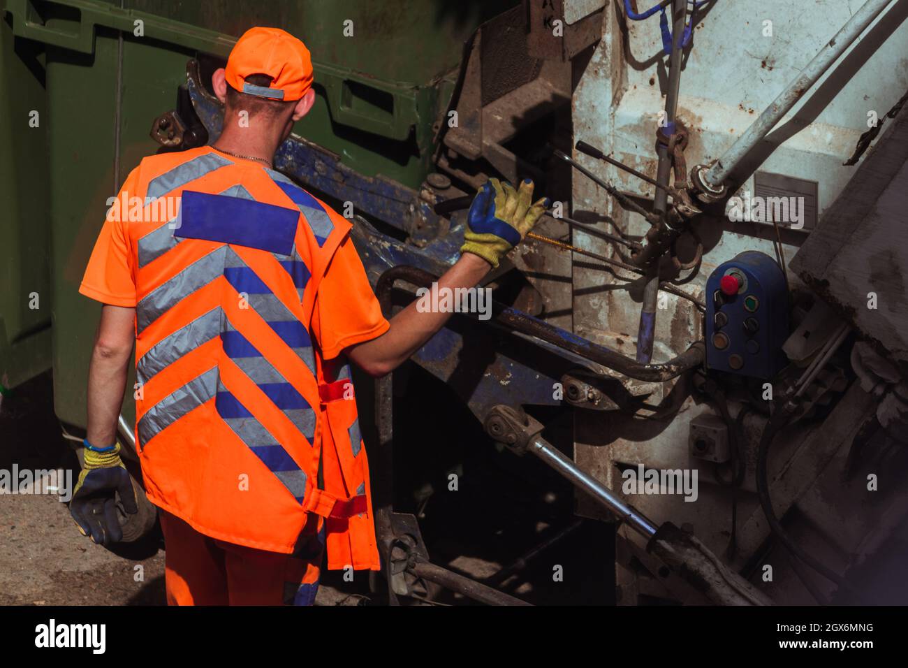 Workers in bright orange uniforms are taking out garbage.  Stock Photo