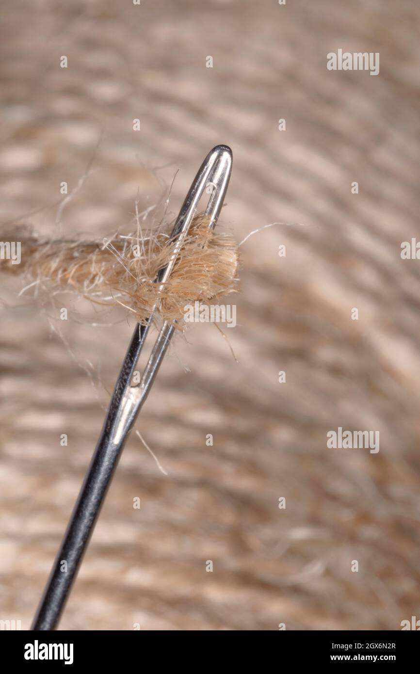 attempt to thread a needle against jute threads Stock Photo Alamy