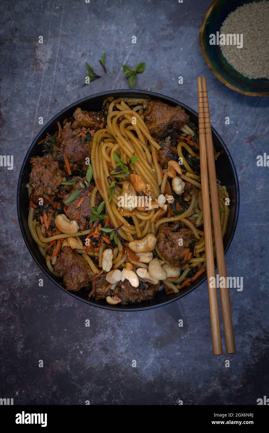 Vegan noodles and seitan stir fry on gray table, copy space Stock Photo