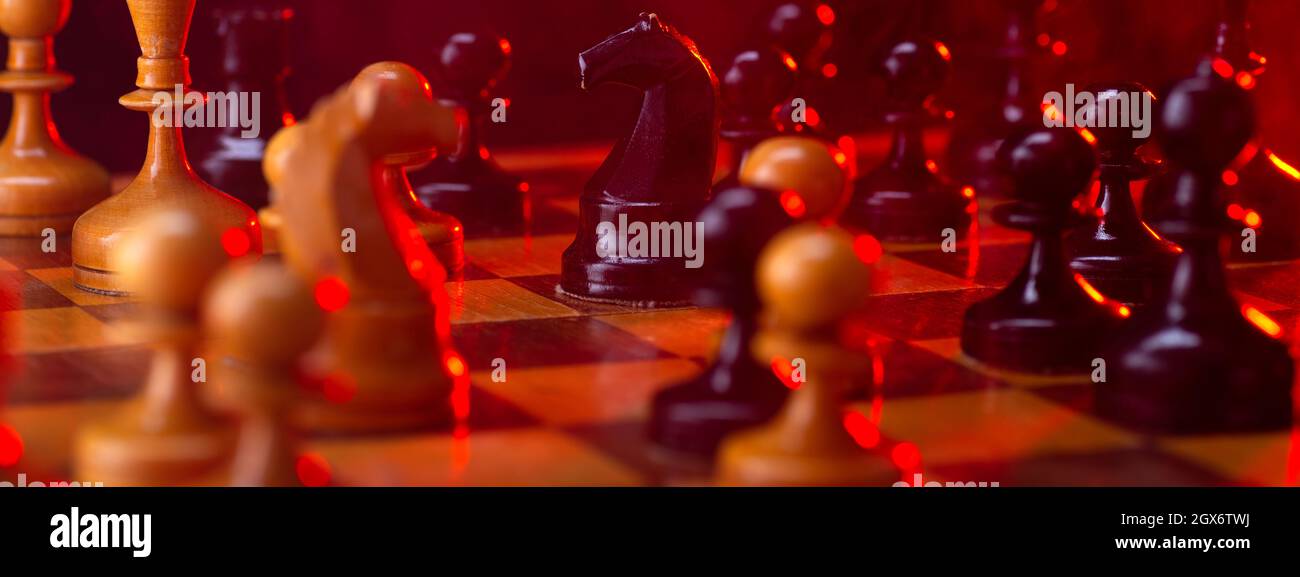 Chess fight, chess pieces on the board, toned in red. Battle fire and smoke. Stock Photo