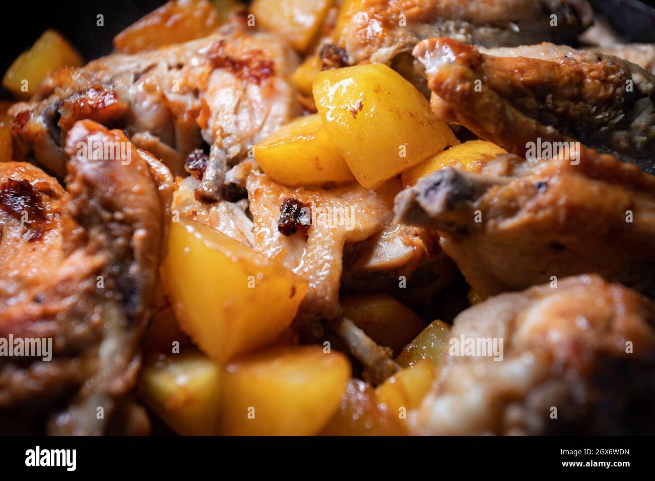 Fried chicken wings with potatoes are cooked in a pan, closeup with