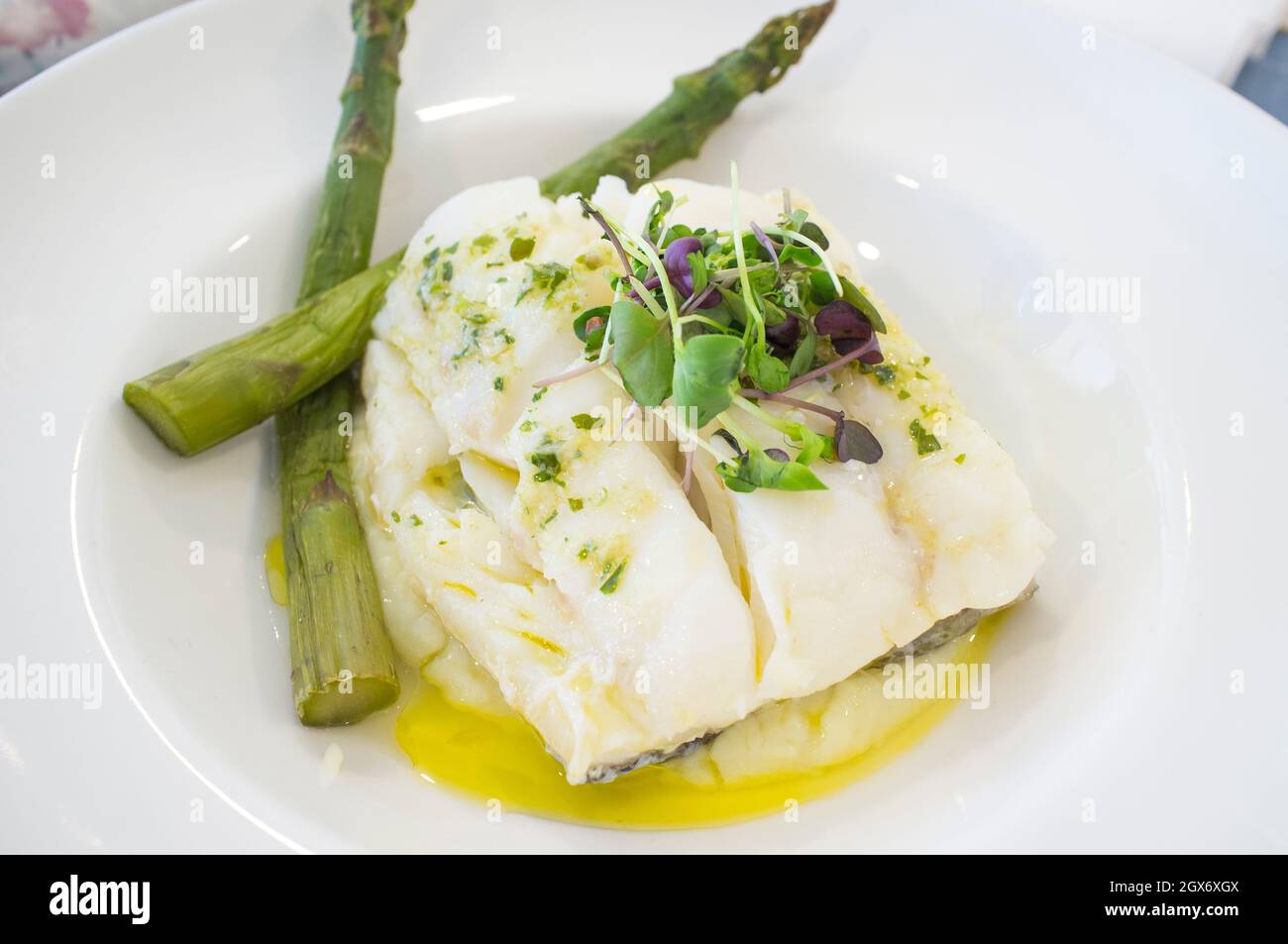 Oven-roasted codfish topped with green wild asparagus and corn salad. Closeup Stock Photo