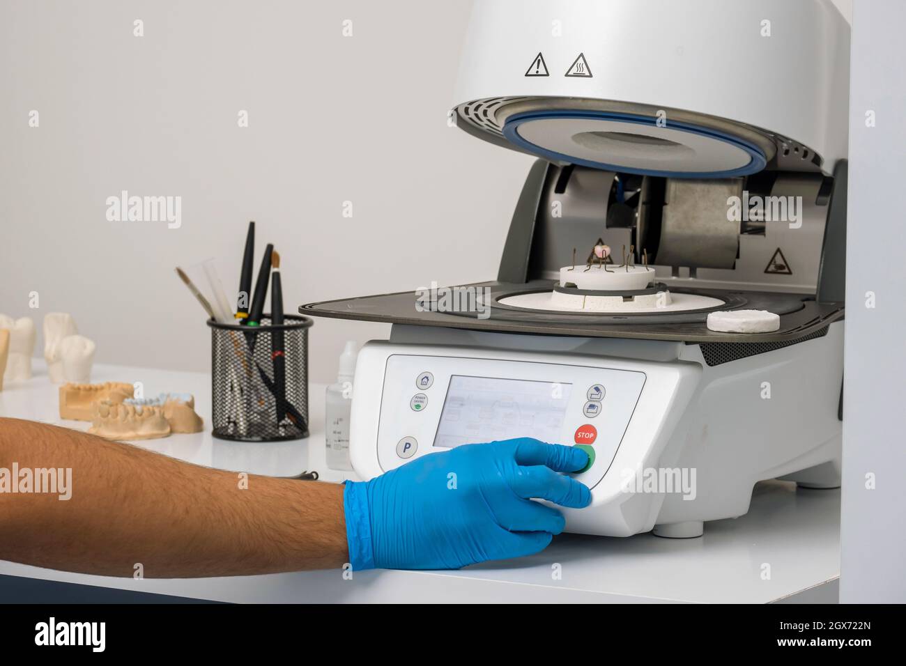 Technician operates high temperature furnace to bake prosthetic ceramic