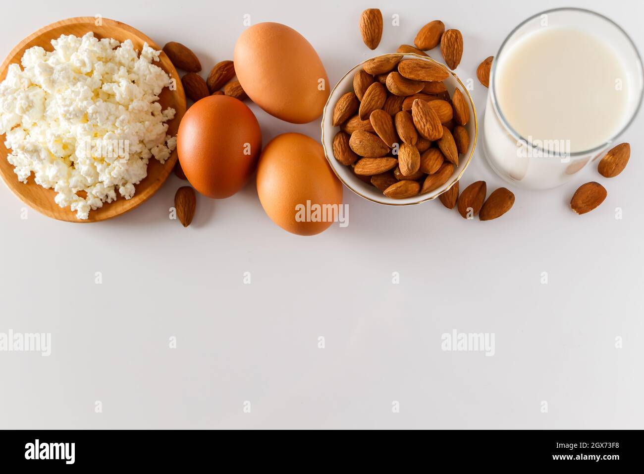 High protein food on a white background - cottage cheese, eggs, nuts. A set of healthy foods for a balanced diet. Stock Photo