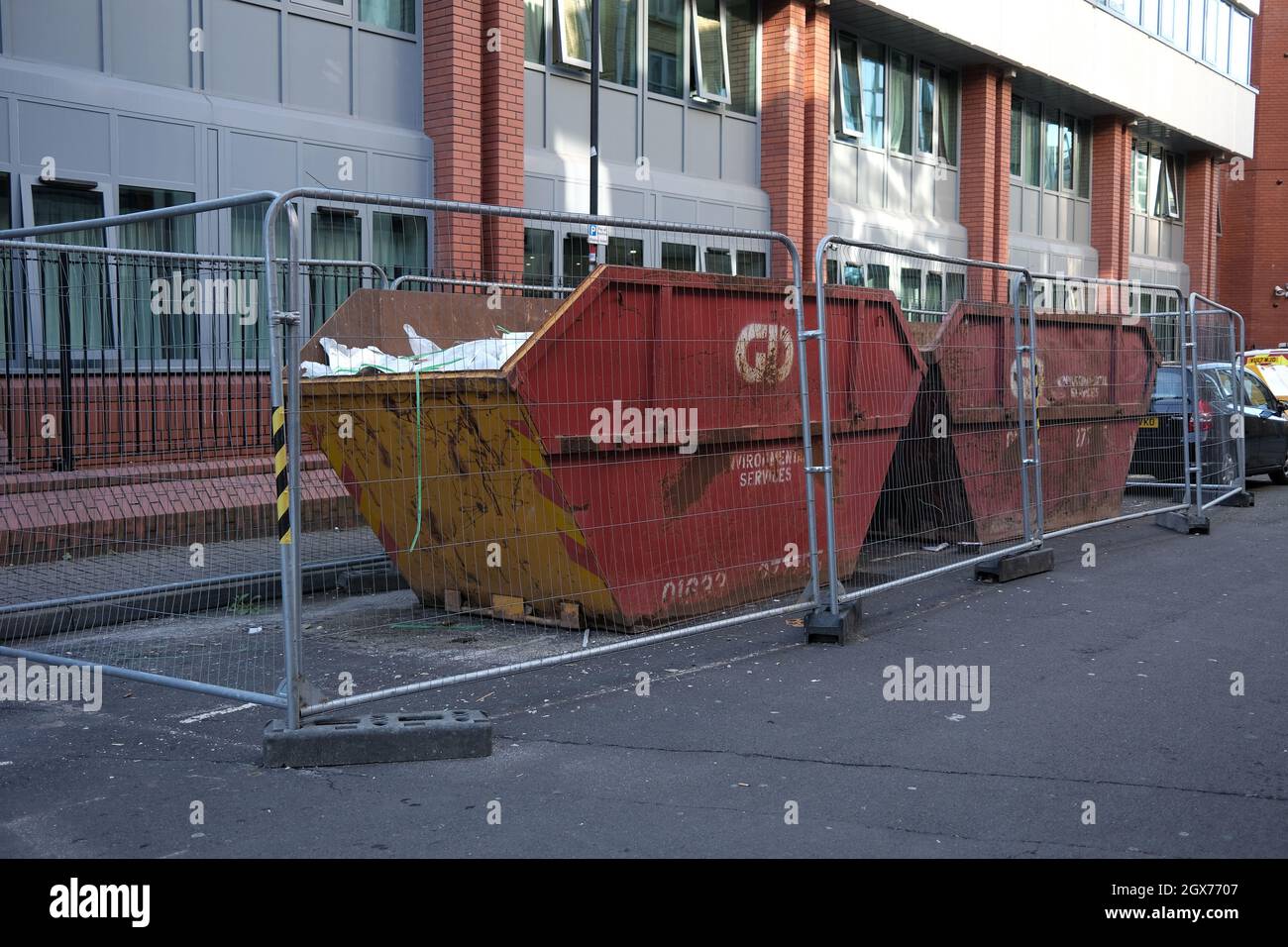 September 2021 - Two large builders skips placed on the road within a secure Heras fenced compound in a back street in Bristol, England, UK. Stock Photo